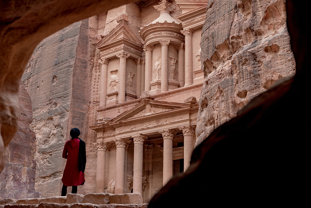 a woman stands at the entrance to Petra, the archaeological city in Jordan