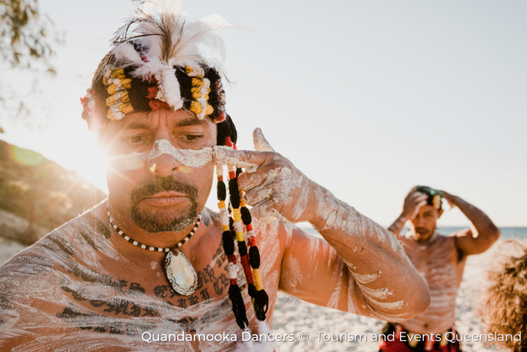 a Quandamooka Dancer applies [aint to his face in a ceremonial style