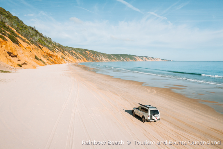 a 4WD vehicle drives along the sand on Rainbow Beach, on the Sunshine Coast, Queensland